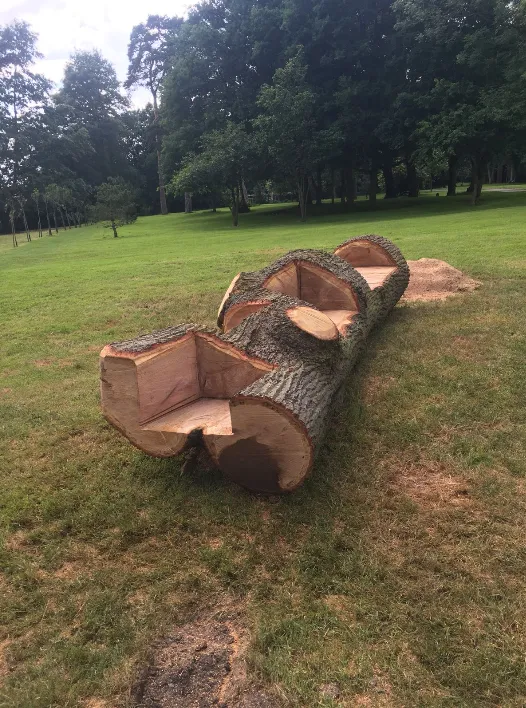 A wooden bench made out of logs in a park.
